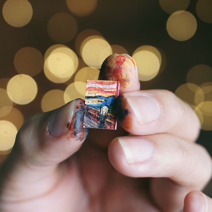 Miniature paper figures: A miniature version of The Scream painting held between paint-stained fingers, showing immense detail.
