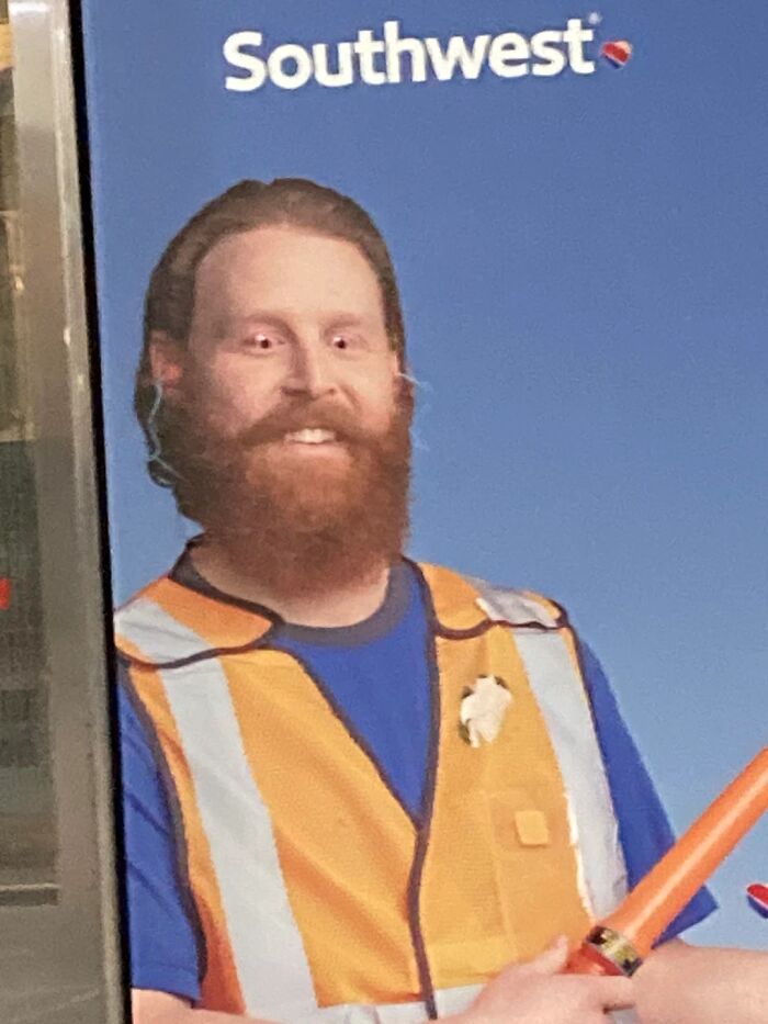 A smiling man with a beard and orange vest, part of the chaotic and memorable moments at airports.