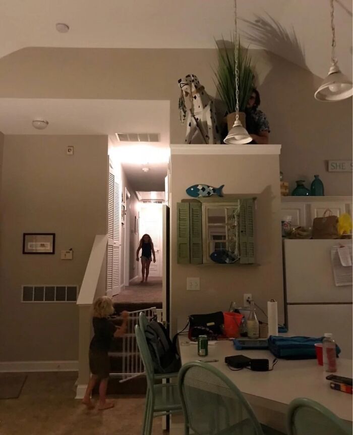Child holding a gate with shadow of a person on wall in home interior
