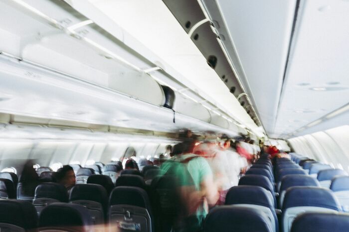 Blurred view of plane passengers walking in airplane aisle during boarding