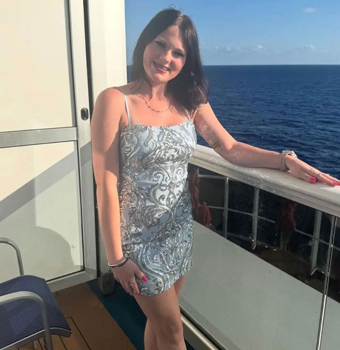 Young woman posing on cruise ship balcony in a patterned dress