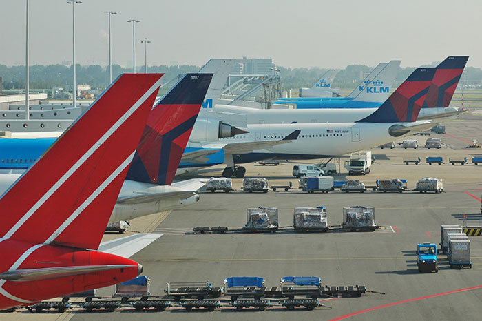 Airline planes on a tarmac with luggage carts, revealing industry secrets about flying.