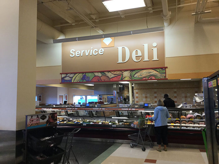 A customer browsing the service deli at a grocery store, highlighting industry secrets in retail.