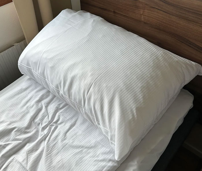 A close-up of a white pillow and bed with striped sheets. Industry secrets customers were never meant to hear.