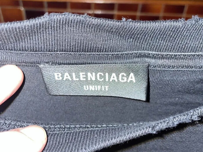Close-up of a BALENCIAGA label on a black garment, exposing industry secrets about clothing manufacturing.