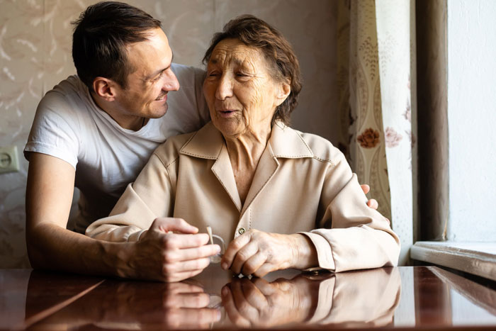 A man embracing an elderly woman at a table, representing family at grandma's funeral. A man embracing an elderly woman at a table, representing family at grandma's funeral.