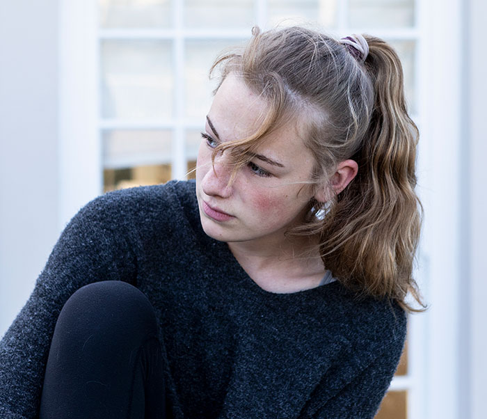 A young woman, representing an introverted girlfriend, looks away thoughtfully, likely contemplating a bar crawl for her boyfriend's birthday. A young woman, representing an introverted girlfriend, looks away thoughtfully, likely contemplating a bar crawl for her boyfriend's birthday.