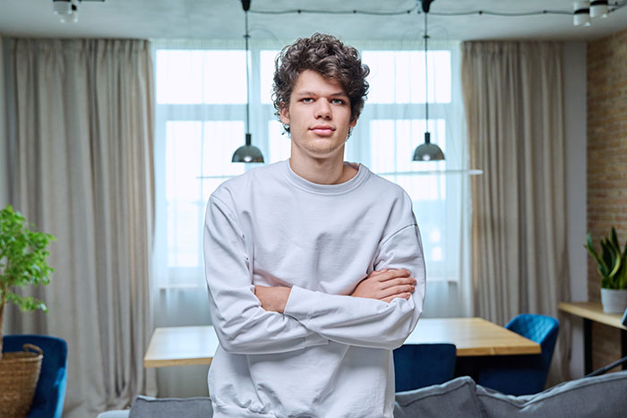 Man begs introverted GF to go to a bar crawl. A young man with curly hair and a white sweatshirt stands in a living room. Man begs introverted GF to go to a bar crawl. A young man with curly hair and a white sweatshirt stands in a living room.