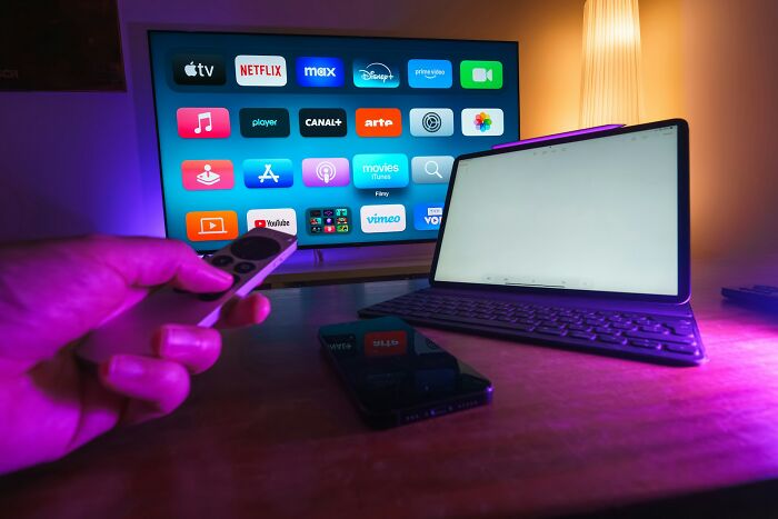 Remote control pointed at smart TV with streaming apps for entertainment