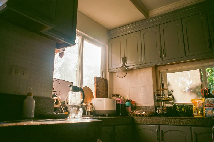 Sunlight streams into a kitchen with light-colored cabinets and various appliances on the counter. People hid their true selves.
