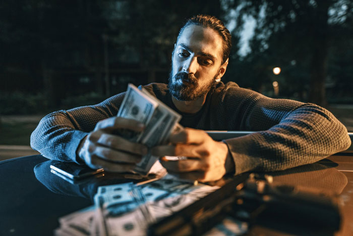 A man counting stacks of money, representing the stolen $361 and the employee's revenge by exposing thieves.