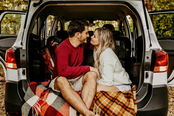 A loving couple intimately sharing a moment in the back of an SUV, a moment that makes women decide to marry their partner.