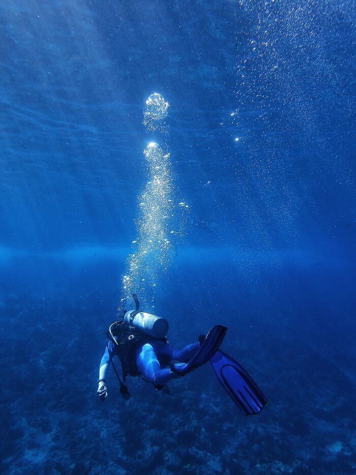 Scuba diver ascending with bubbles underwater clear blue water diving story