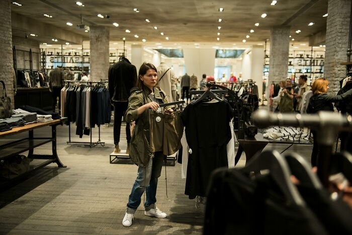 Woman browsing clothing racks inside fashion retail store
