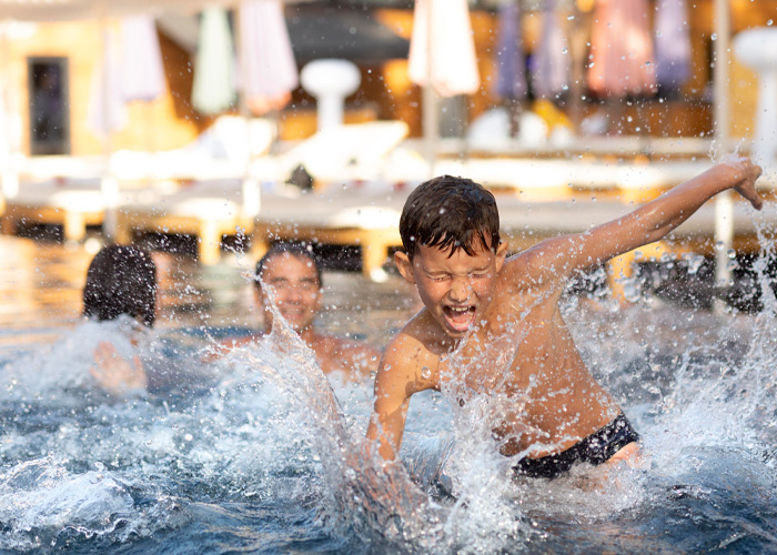 Happy child splashing and playing in a swimming pool with others