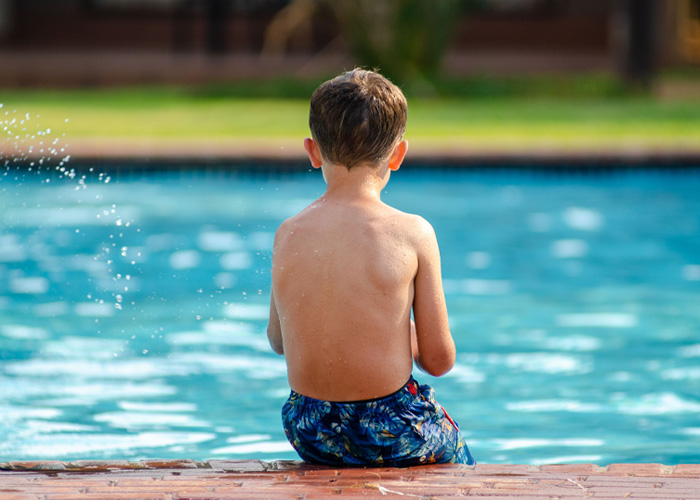 Seven-year-old boy sitting by a hotel swimming pool