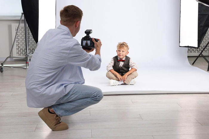 Photographer taking pictures of a young boy in a studio setup