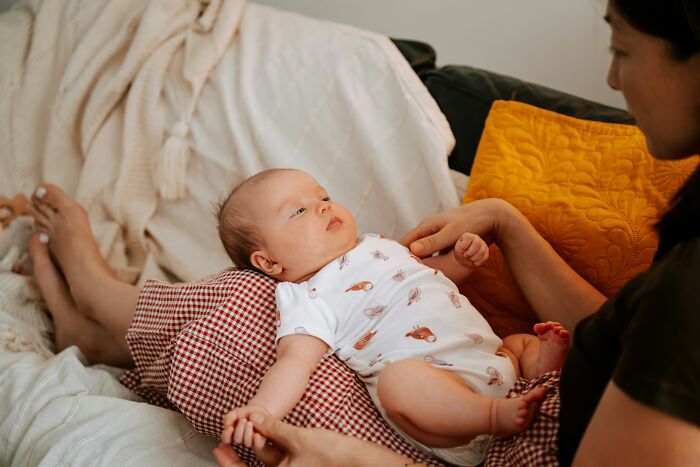 Mother holding baby on couch with cozy home setting