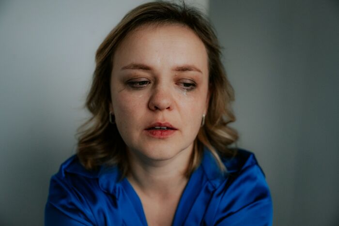 A woman with tears on her face, looking sad, representing the emotional impact of double lives exposed.