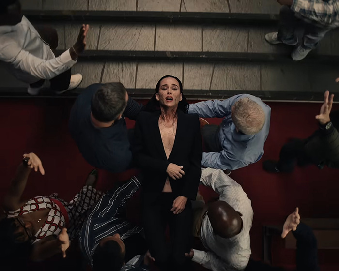 Katy Perry lying on the ground, surrounded by people, in a horrifying new video scene.