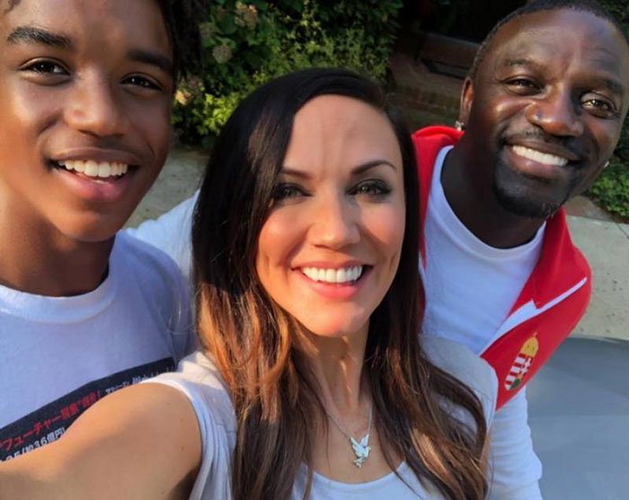 Akon poses smiling with two people outdoors