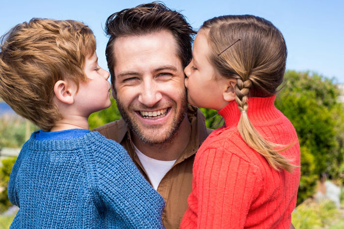 A happy father getting kisses from two stepkids, while his daughter feels replaced. A happy father getting kisses from two stepkids, while his daughter feels replaced.
