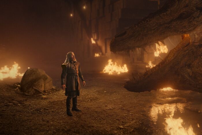 A Targaryen man stands before a large dragon, symbolizing the powerful House of the Dragon family tree. A Targaryen man stands before a large dragon, symbolizing the powerful House of the Dragon family tree.