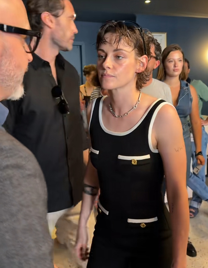 Kristen Stewart looking uncomfortable as a man invades her personal space, surrounded by others.