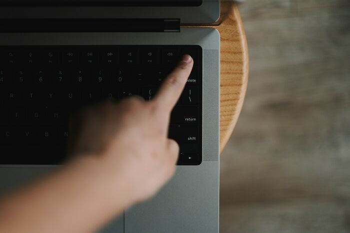 A hand pressing the power button on a laptop keyboard, a silly solution to start working.