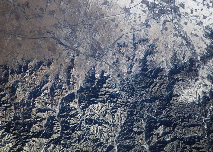 Aerial view of mountainous landscape with snow patches and valleys
