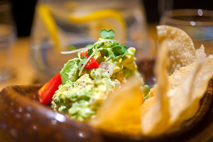 Fresh guacamole with chips at a restaurant, served without onions due to a claimed allergy to avoid emergency room.