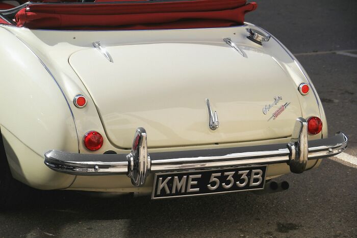 A vintage cream car with a red soft top, highlighting an unsolved mystery with its classic design.