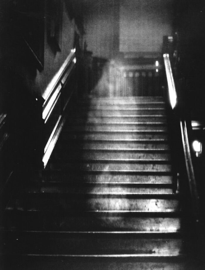 Black and white creepy photo showing ghostly figure on staircase