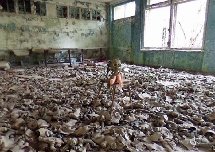 Abandoned room filled with scattered gas masks and tripod stand in eerie photo