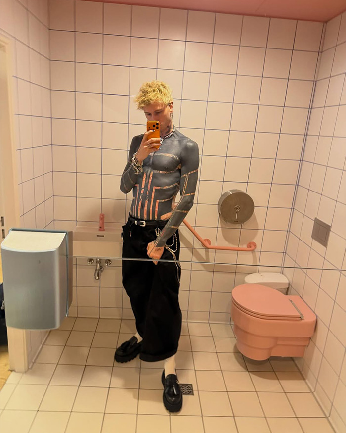 Man with blackout tattoos taking a mirror selfie in a bathroom, revealing the trend's reality.