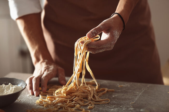 Hands preparing fresh pasta on a floured surface, one of the weirdly hard to forget facts.