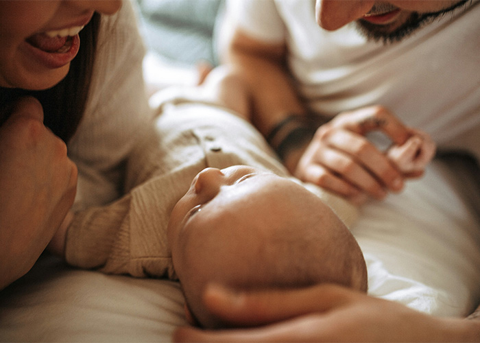 Parents happily interacting with their baby lying down Parents happily interacting with their baby lying down