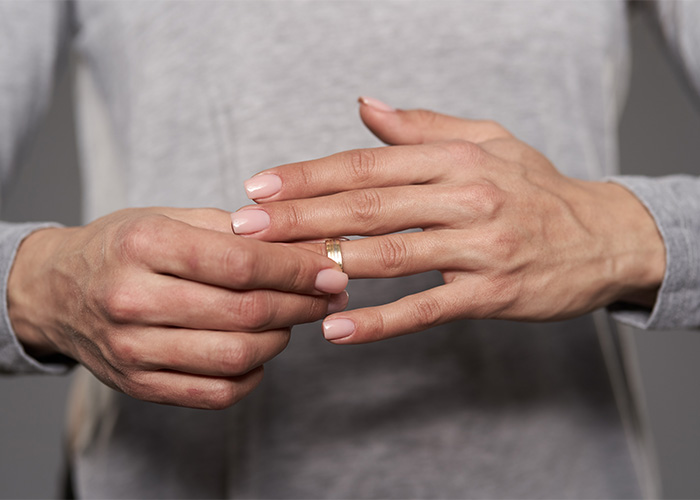 Close-up of a woman removing a wedding ring from her finger Close-up of a woman removing a wedding ring from her finger