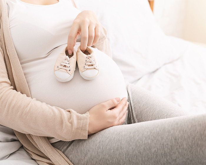 A pregnant woman holding baby shoes, related to the classmate using fake photos to pretend to have a family. A pregnant woman holding baby shoes, related to the classmate using fake photos to pretend to have a family.