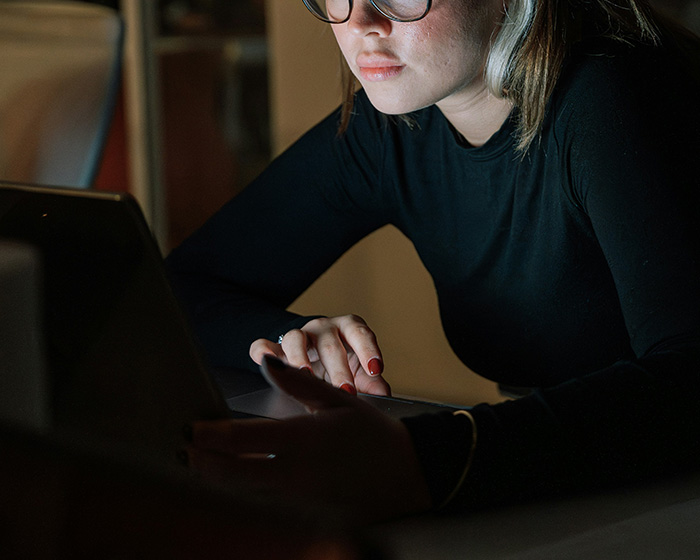A woman on a laptop discovers fake photos, feeling traumatized by the classmate's deception. A woman on a laptop discovers fake photos, feeling traumatized by the classmate's deception.