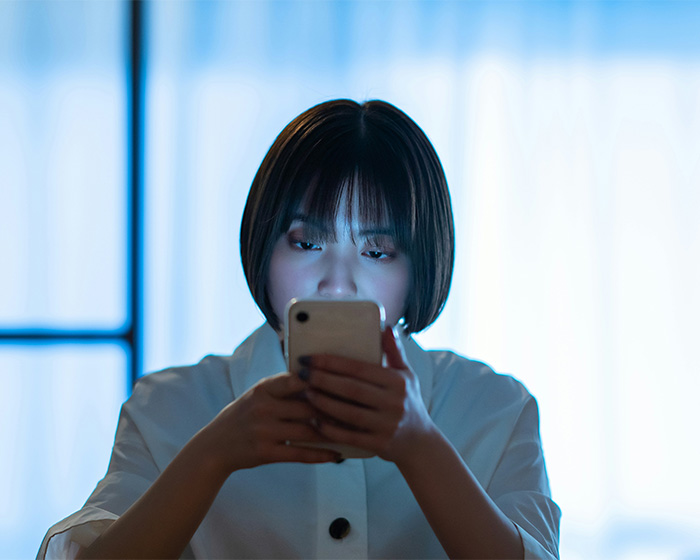 A woman looking traumatized while using her phone, discovering old classmate's fake photos. A woman looking traumatized while using her phone, discovering old classmate's fake photos.