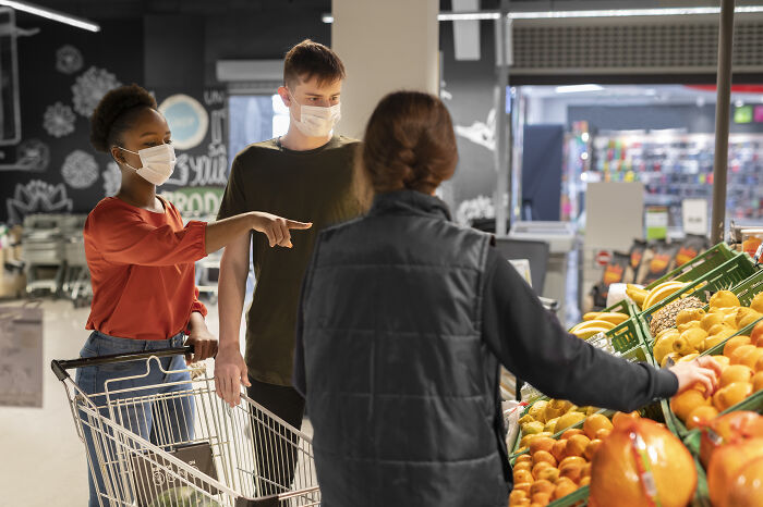 People wearing masks, visiting the US, are seen shopping for fresh produce in a supermarket.