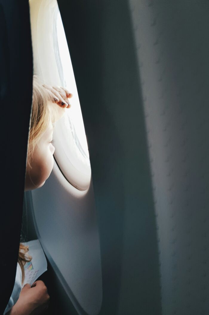 Child looking out airplane window during flight