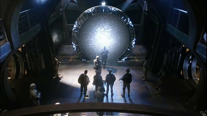 Stargate gate activation with team approaching in sci-fi setting Stargate gate activation with team approaching in sci-fi setting