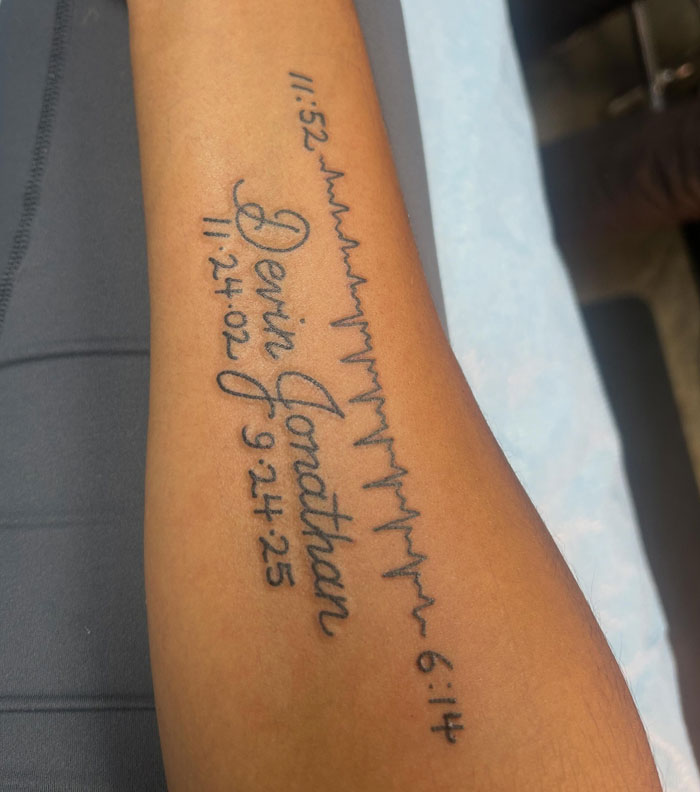 An arm tattoo showing names and dates with a heartbeat line, representing significant tattoos.