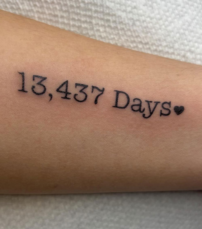 A close-up of a forearm with a tattoo reading 13,437 Days with a small heart, meaningful tattoos.