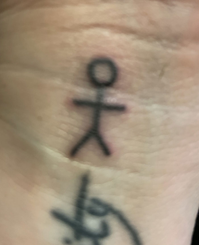 Small stick figure tattoo on a person's hand, illustrating a simple yet profound tattoo with hidden meaning.