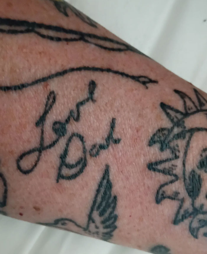 Forearm tattoos including script Love Dad, with other designs, symbolizing significant meaning.