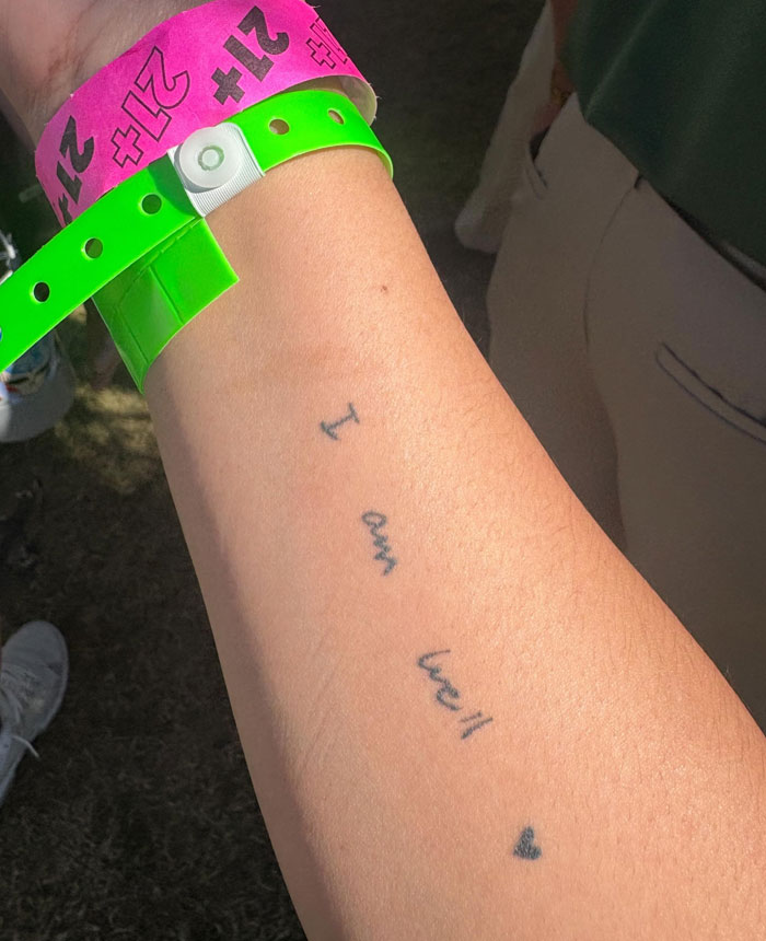 Arm tattoos with the words I am well and a small heart, showcasing meaningful personal expression.