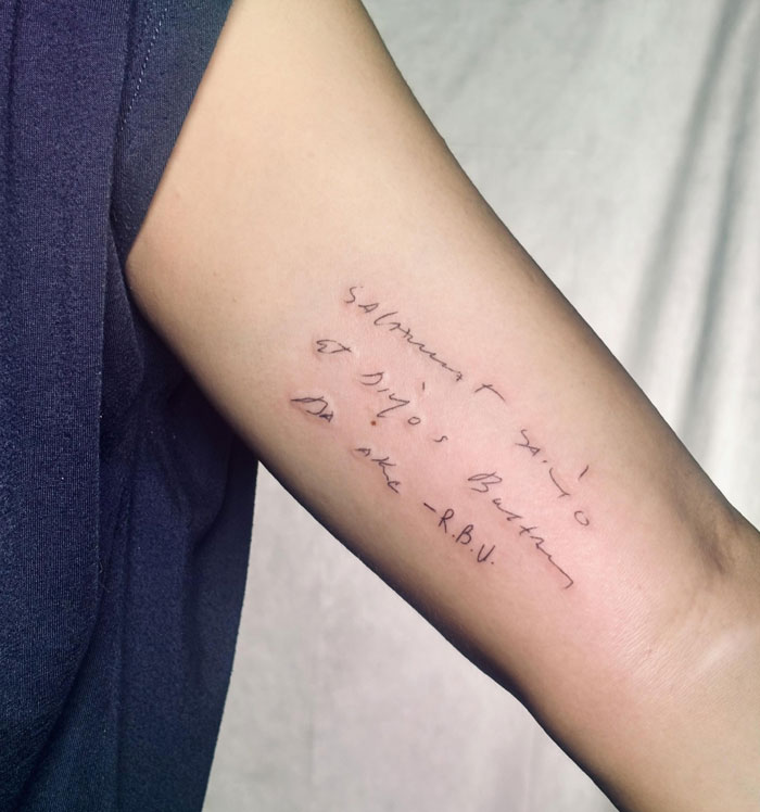 Forearm with a delicate script tattoo, representing deeply meaningful tattoos and personal body art.